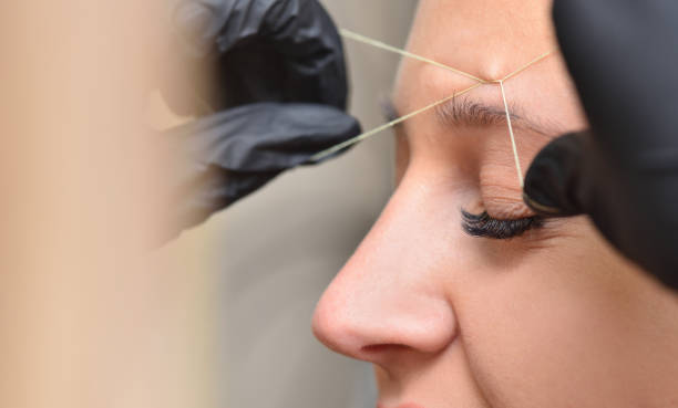 Eyebrow correction procedure with thread and woman face close up.